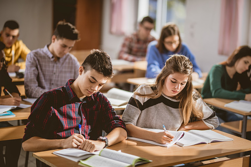 Large group of students writing an exam during a class in the classroom.